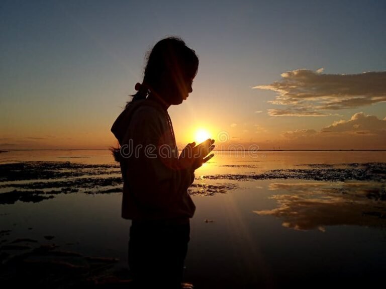 manos en oracion con un amanecer